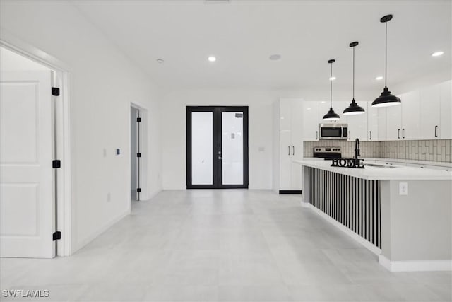 kitchen featuring backsplash, french doors, appliances with stainless steel finishes, white cabinets, and light countertops