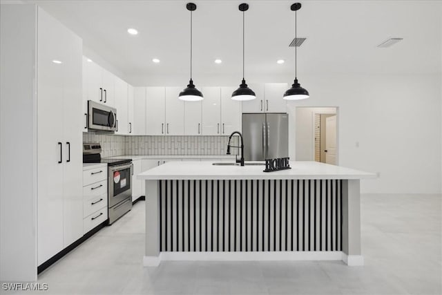 kitchen with decorative backsplash, a center island with sink, appliances with stainless steel finishes, and light countertops