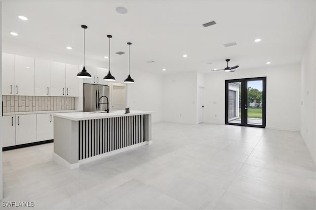 kitchen featuring visible vents, tasteful backsplash, white cabinetry, freestanding refrigerator, and light countertops