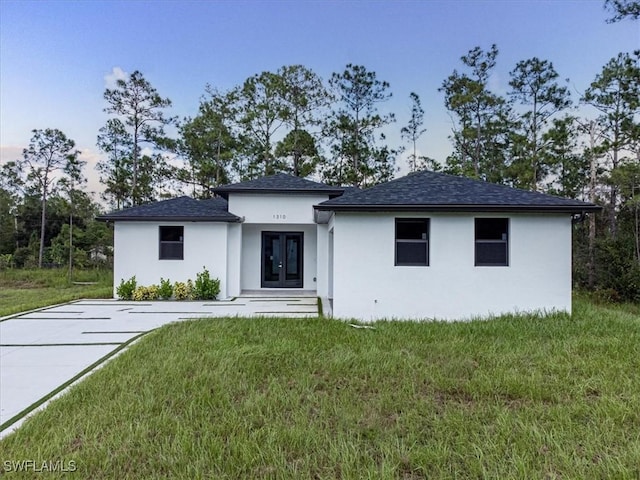 view of front of house with stucco siding, french doors, and a front yard