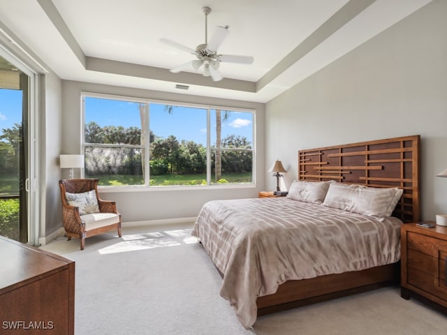 bedroom featuring ceiling fan, light colored carpet, and a tray ceiling