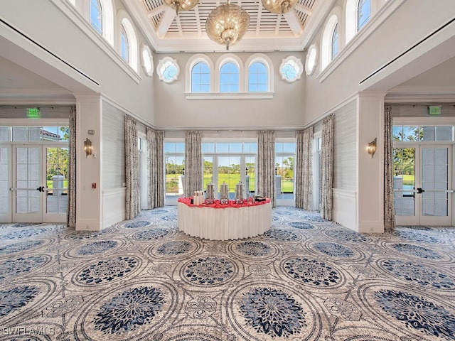 interior space with a healthy amount of sunlight, a towering ceiling, and french doors