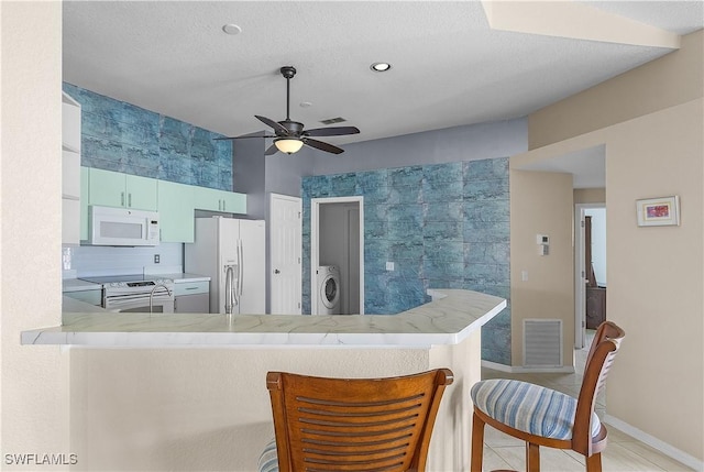 kitchen featuring ceiling fan, tasteful backsplash, kitchen peninsula, washer / clothes dryer, and white appliances