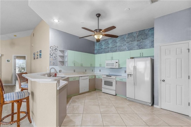 kitchen featuring kitchen peninsula, a kitchen breakfast bar, white appliances, ceiling fan, and sink