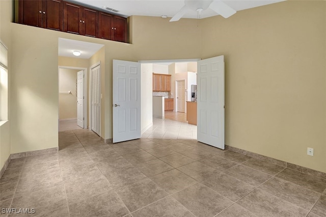 spare room with ceiling fan, light tile patterned floors, and a high ceiling