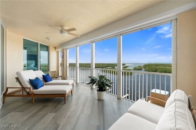 sunroom / solarium with a wealth of natural light, a water view, and ceiling fan