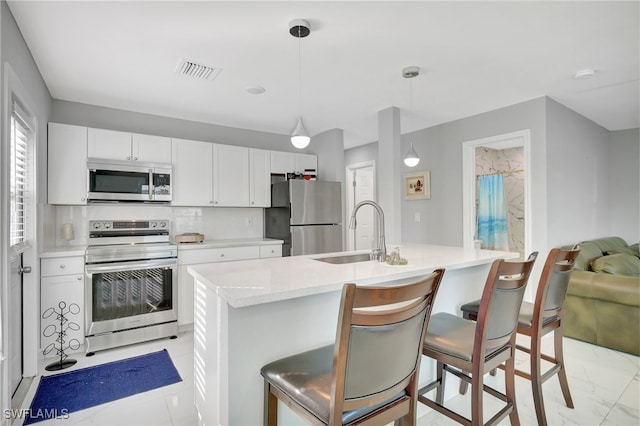 kitchen with backsplash, sink, hanging light fixtures, appliances with stainless steel finishes, and a breakfast bar area