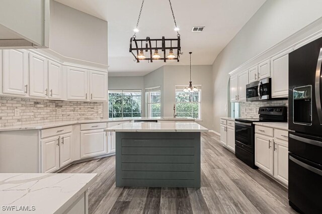 kitchen featuring black appliances, light hardwood / wood-style floors, a chandelier, and white cabinetry