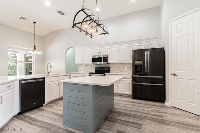 kitchen with pendant lighting, light stone countertops, appliances with stainless steel finishes, white cabinets, and light hardwood / wood-style floors