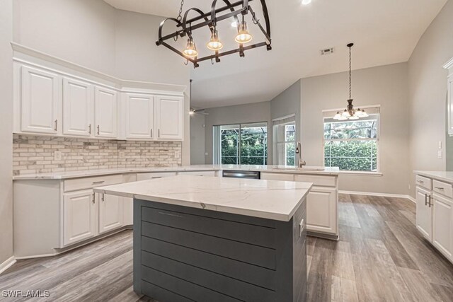 kitchen with kitchen peninsula, sink, ceiling fan with notable chandelier, and white cabinets