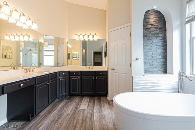 bathroom featuring high vaulted ceiling, a bathtub, hardwood / wood-style flooring, and vanity