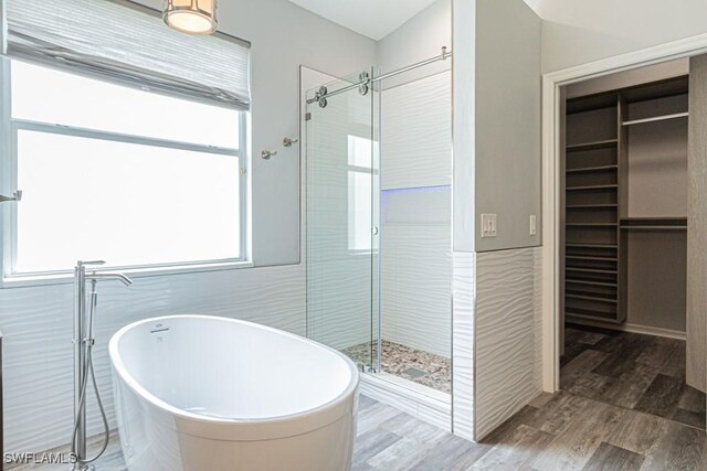 bathroom with hardwood / wood-style flooring and shower with separate bathtub