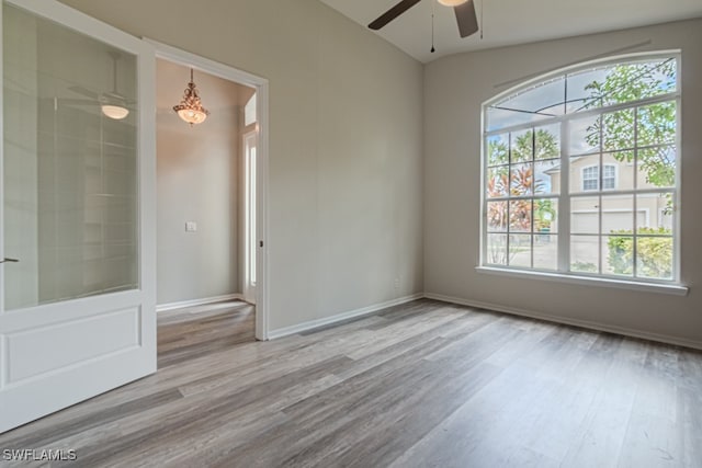 empty room with lofted ceiling, wood-type flooring, and ceiling fan