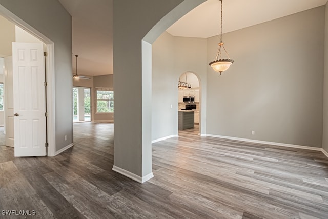 empty room with dark wood-type flooring, ceiling fan, and high vaulted ceiling