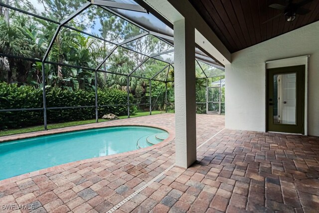 view of pool with ceiling fan, a patio area, and glass enclosure