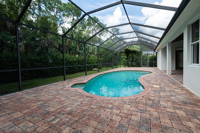 view of pool featuring glass enclosure and a patio