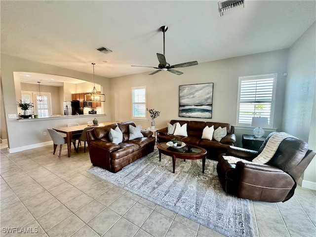 living room featuring light tile patterned flooring and ceiling fan with notable chandelier