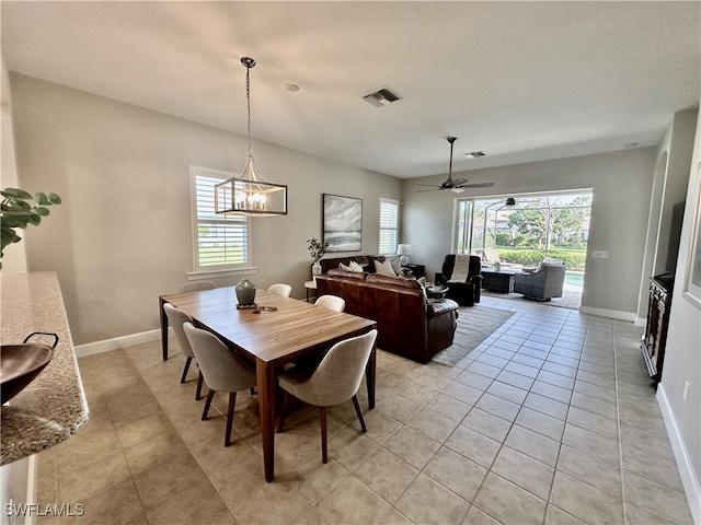 dining room with ceiling fan with notable chandelier, light tile patterned floors, and plenty of natural light