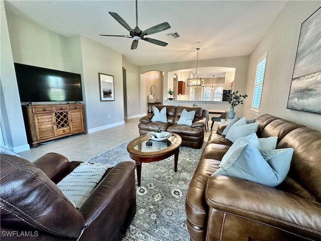 tiled living room featuring ceiling fan with notable chandelier