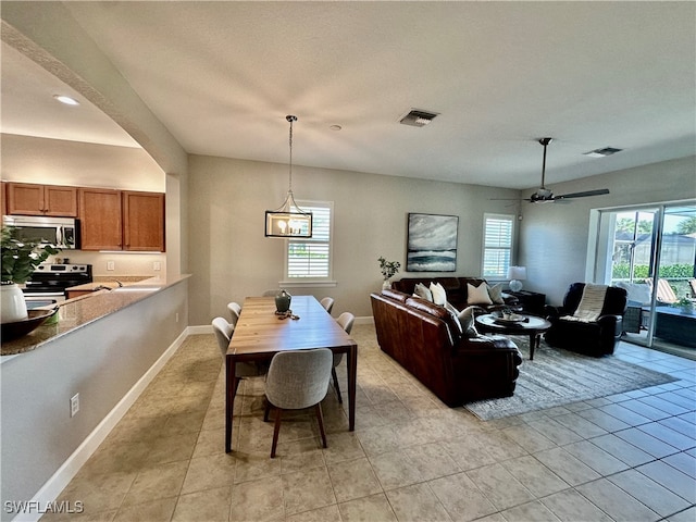 tiled dining area featuring ceiling fan with notable chandelier and a wealth of natural light