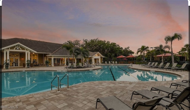 pool at dusk with a patio area