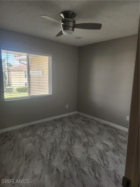 unfurnished room with ceiling fan and a textured ceiling