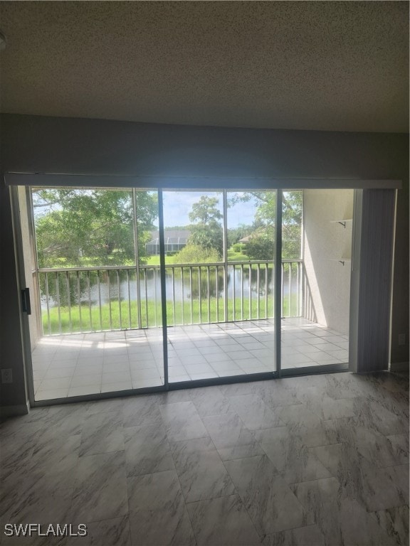 doorway to outside with a water view and a textured ceiling