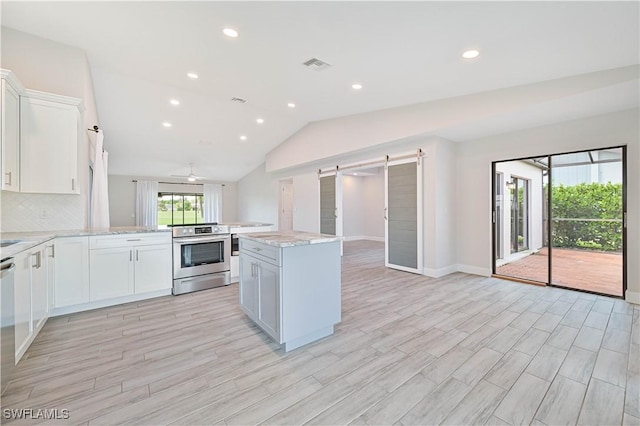 kitchen with visible vents, a peninsula, stainless steel appliances, white cabinets, and a barn door