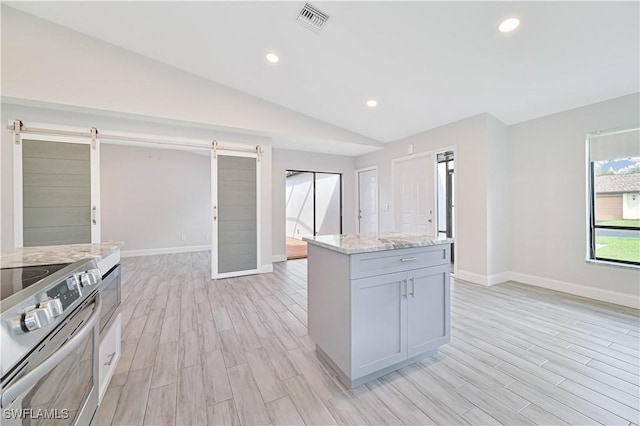 kitchen featuring light wood finished floors, visible vents, a barn door, and vaulted ceiling