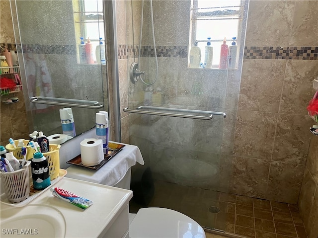 bathroom featuring vanity, toilet, and a shower with shower door