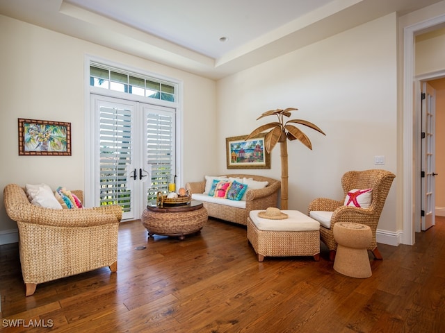 living area with a tray ceiling and dark hardwood / wood-style floors