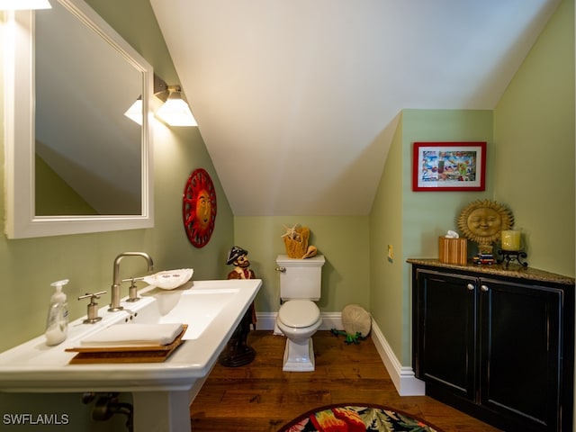 bathroom featuring toilet, wood-type flooring, vaulted ceiling, and sink