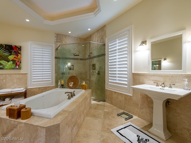 bathroom with sink, a raised ceiling, crown molding, independent shower and bath, and tile walls