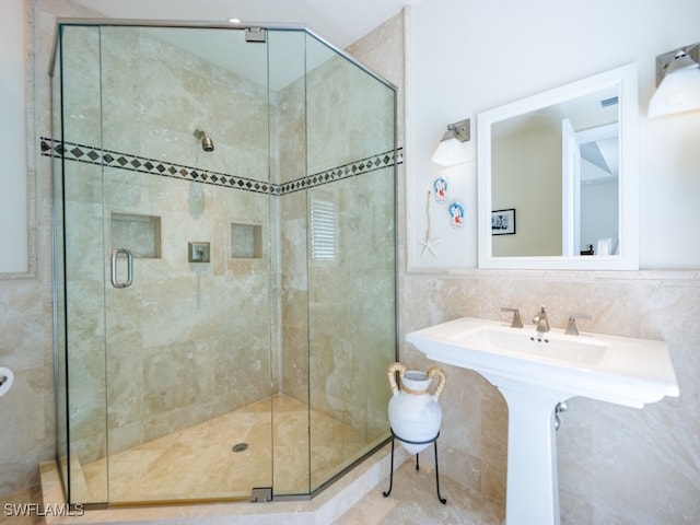 bathroom with decorative backsplash, sink, walk in shower, and tile walls