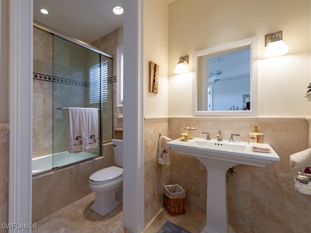 bathroom featuring shower / bath combination with glass door, tile patterned floors, toilet, and tile walls