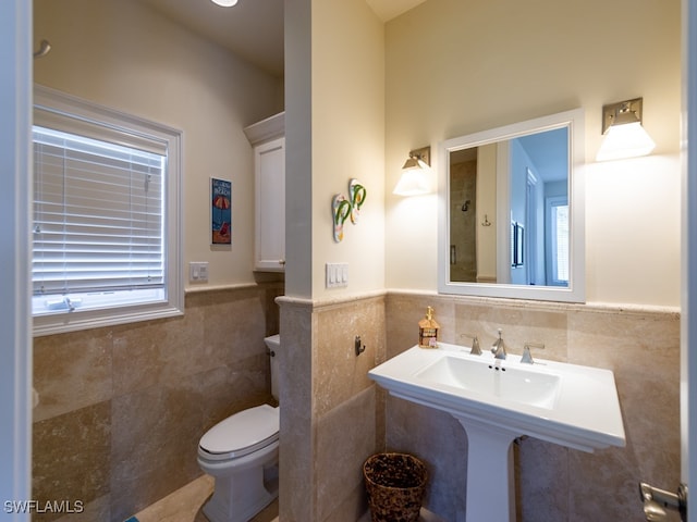 bathroom with toilet and tile walls