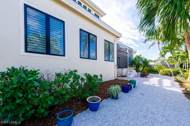 view of side of property with glass enclosure, a patio area, and an outdoor fire pit