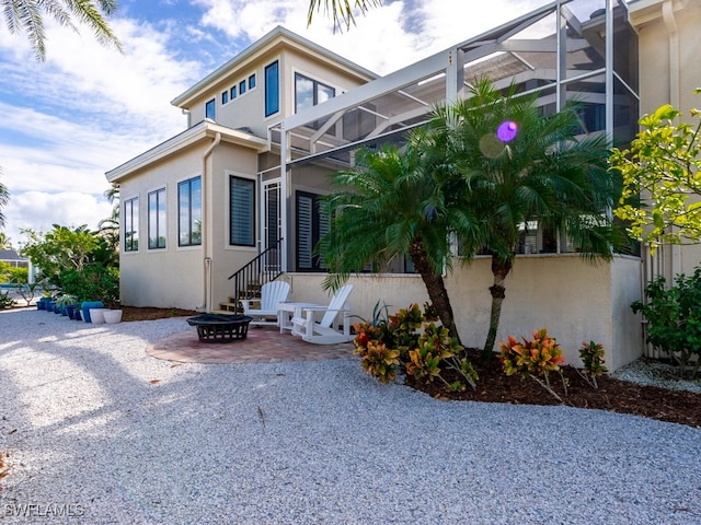 view of side of home with a patio area, a lanai, and an outdoor fire pit