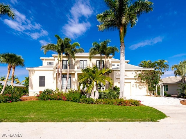 mediterranean / spanish-style home featuring a balcony, a front lawn, and french doors