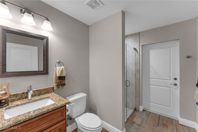 bathroom featuring vanity, toilet, wood-type flooring, and an enclosed shower