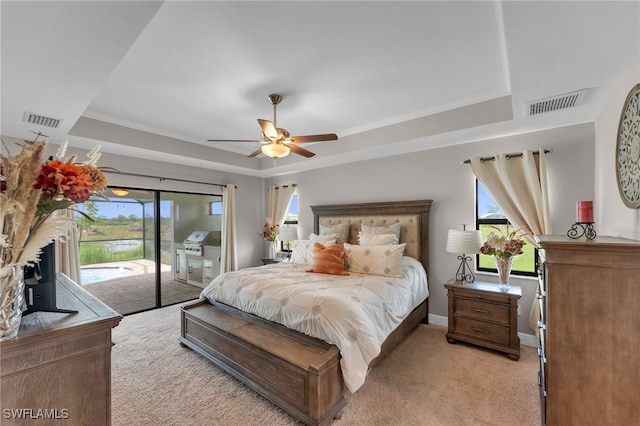 bedroom with light carpet, a tray ceiling, access to outside, ceiling fan, and ornamental molding