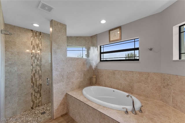 bathroom with a healthy amount of sunlight and separate shower and tub