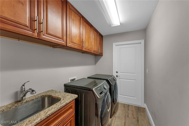 laundry room featuring cabinets, sink, washer and clothes dryer, and light hardwood / wood-style floors