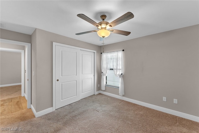 unfurnished bedroom with a closet, light colored carpet, and ceiling fan