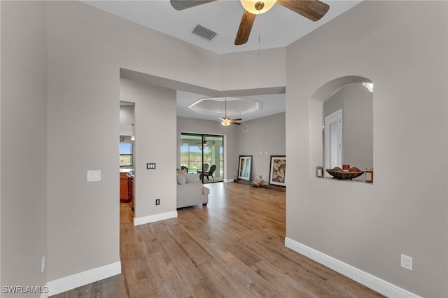 hall featuring light wood-type flooring and a tray ceiling