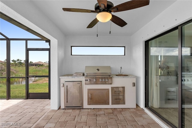 view of patio / terrace featuring a lanai, area for grilling, an outdoor kitchen, and ceiling fan