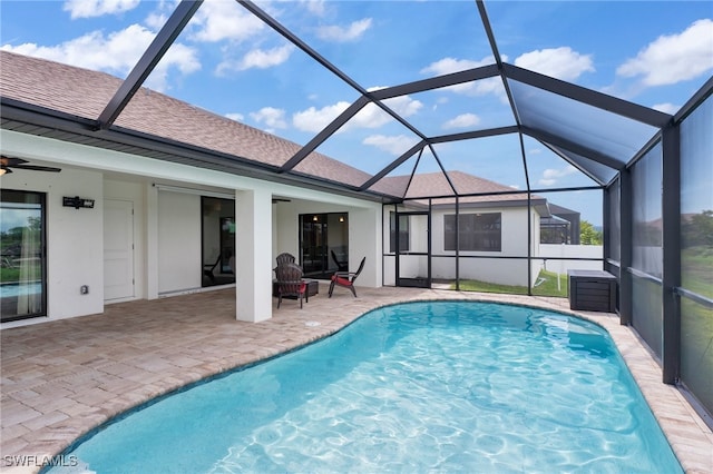 view of swimming pool with glass enclosure, ceiling fan, and a patio