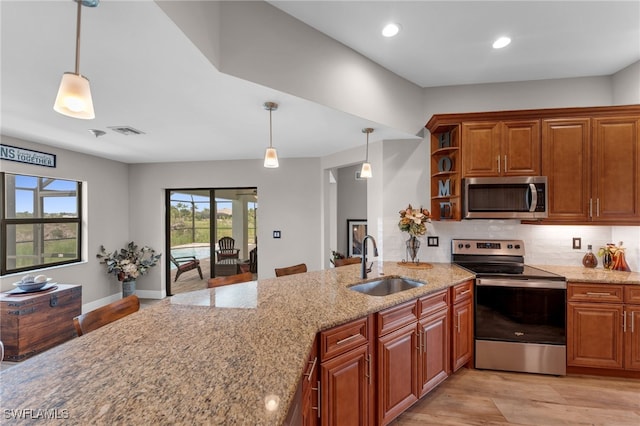 kitchen featuring a kitchen bar, backsplash, stainless steel appliances, decorative light fixtures, and sink