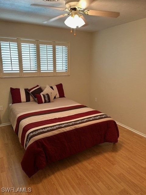 bedroom featuring baseboards, light wood-style floors, and ceiling fan