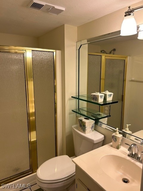 bathroom with vanity, toilet, an enclosed shower, and a textured ceiling